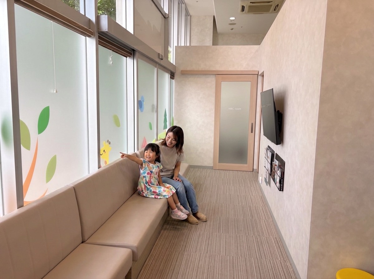 待合のベンチで窓の絵を指さす女の子とお母さん（イメージ）