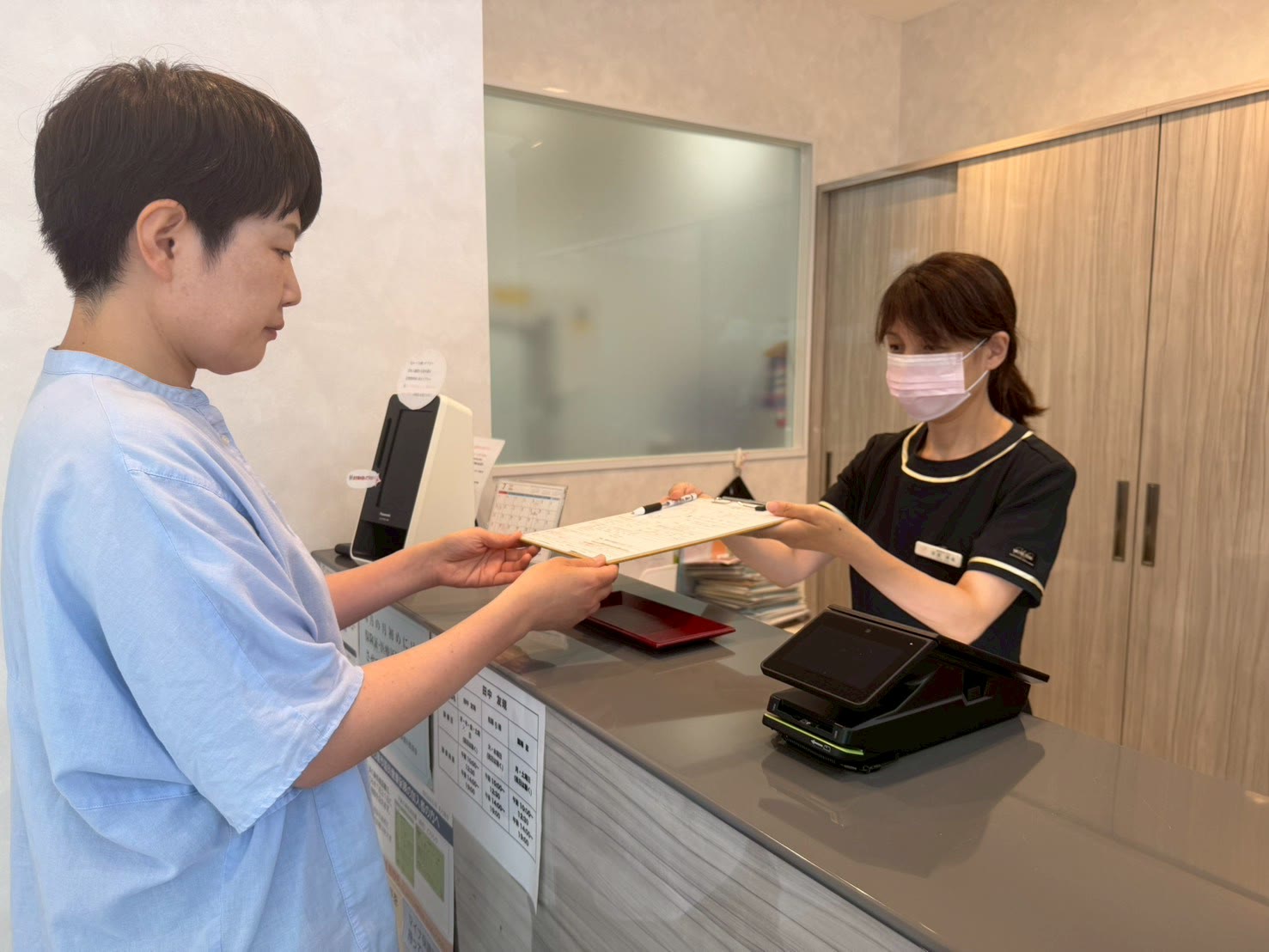 受付で問診票をお渡しするスタッフ